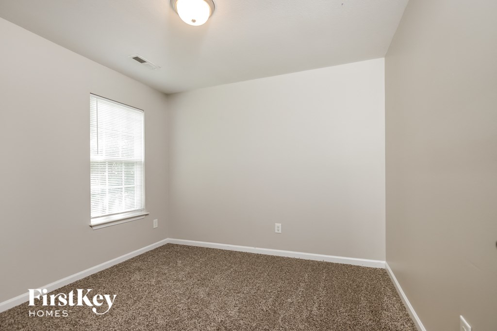 the upstairs bedroom has a carpeted floor and a window
