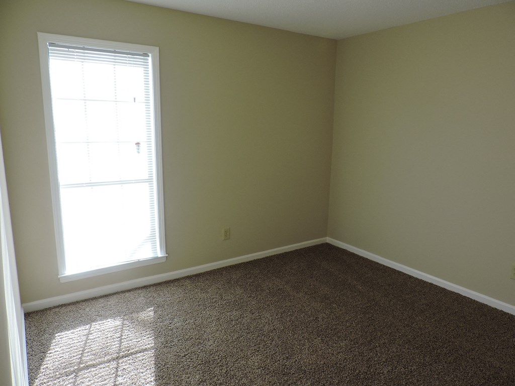 an empty room with a window and a carpet