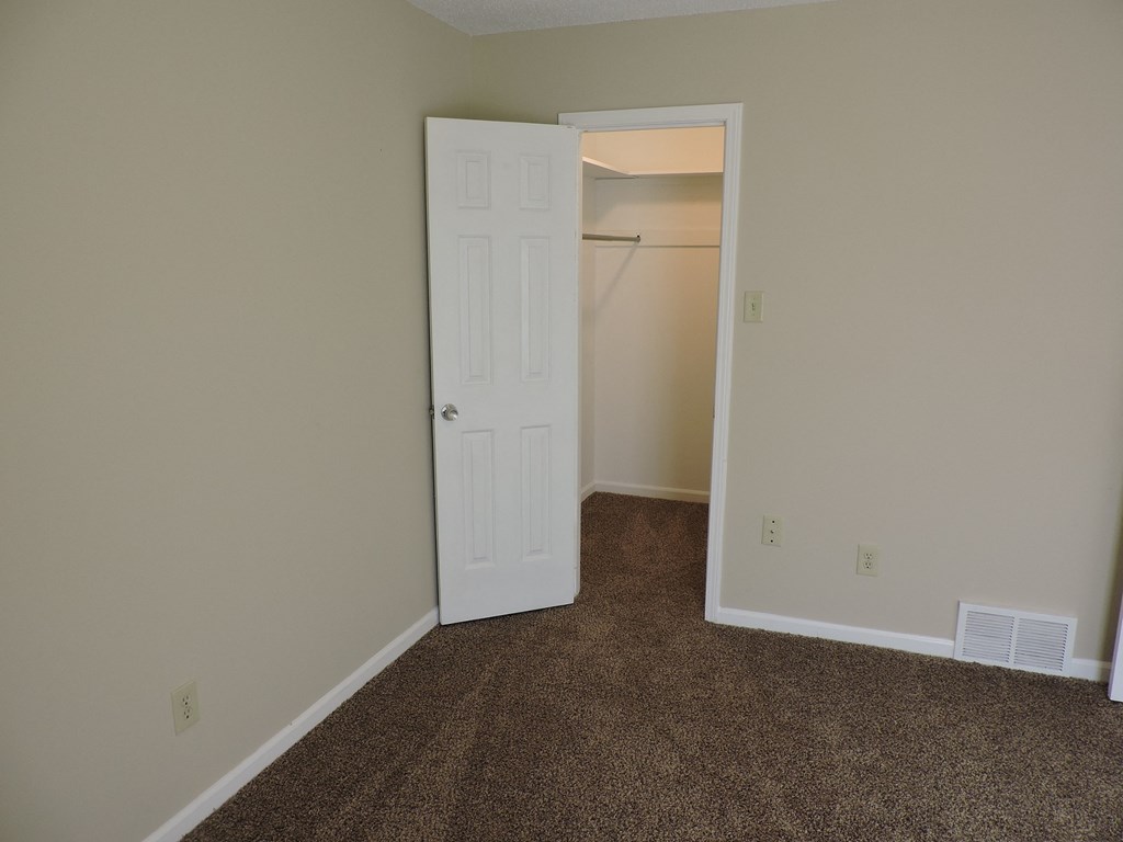 an empty room with a closet and a white door