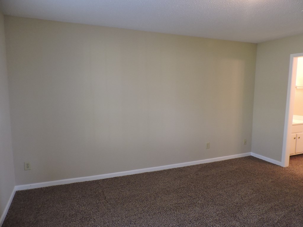 an empty living room with white walls and carpet