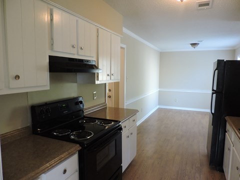 an empty kitchen with black appliances and white cabinets