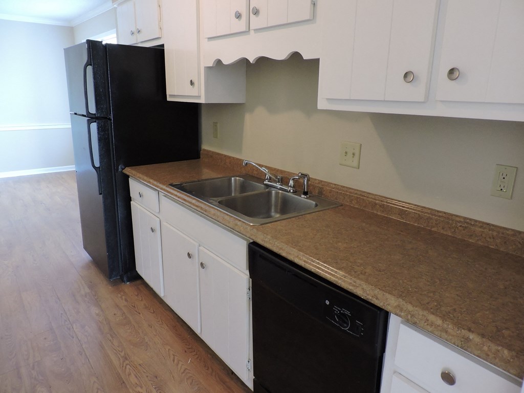 an empty kitchen with white cabinets and a black refrigerator
