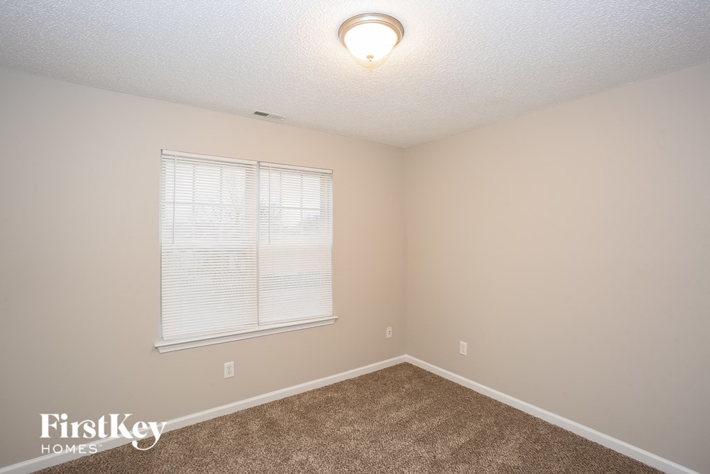 a bedroom with a large window and a carpeted floor