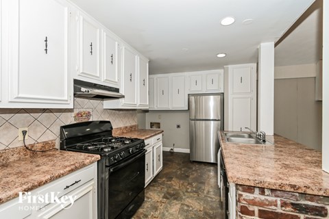 A kitchen with a black stove top oven and a granite counter top.