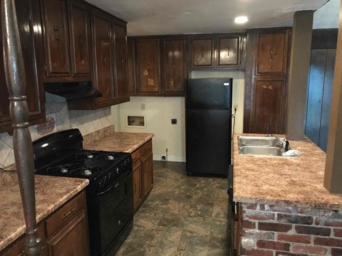 A kitchen with a black refrigerator and a black stove top oven.