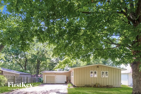 a house with a garage and a tree in front of it