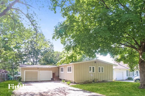 a yellow house with a garage and a tree