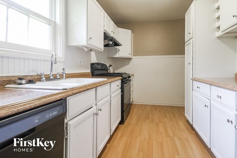 a kitchen with white cabinets and a sink and a stove