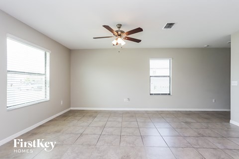 A spacious room with a ceiling fan and tiled floor.