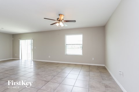 A spacious room with a ceiling fan and two windows.