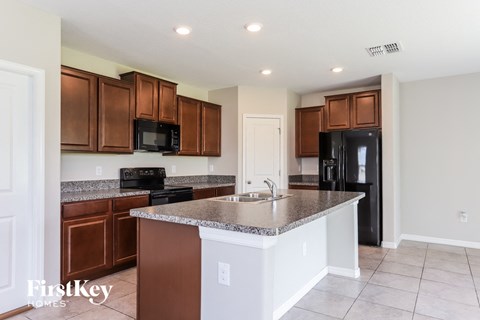 A kitchen with brown cabinets and a black fridge.