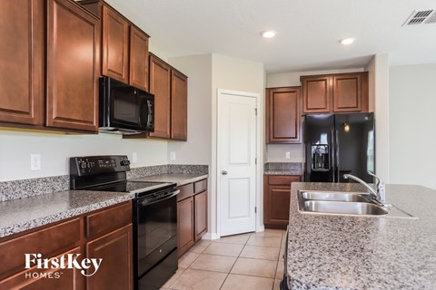 A kitchen with brown cabinets and a black fridge.