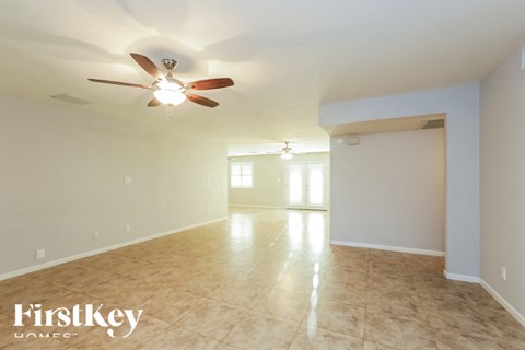 A spacious room with a ceiling fan and tiled flooring.