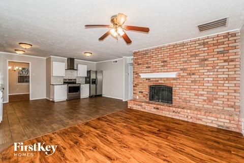 A living room with a brick fireplace and wooden floors.