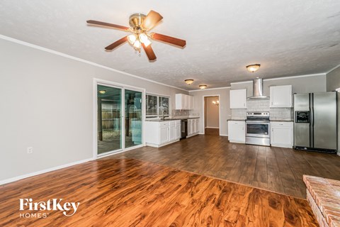 A spacious kitchen with wooden floors and a ceiling fan.
