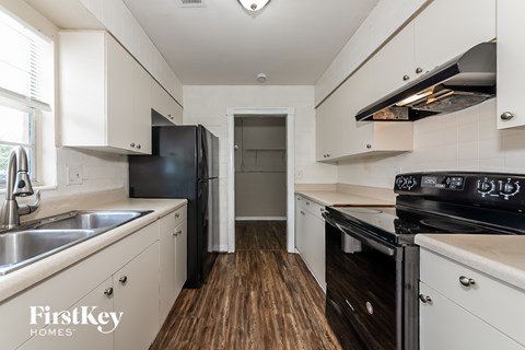 A kitchen with white cabinets and a black stove top oven.