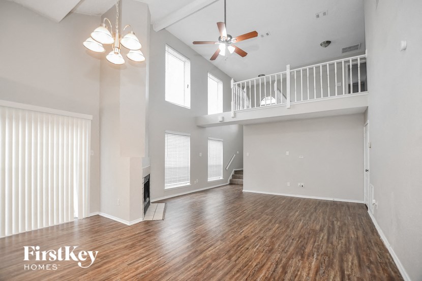 A spacious room with wooden floors and a balcony.