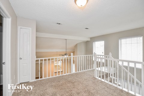 A spacious living room with a carpeted floor and white railings.