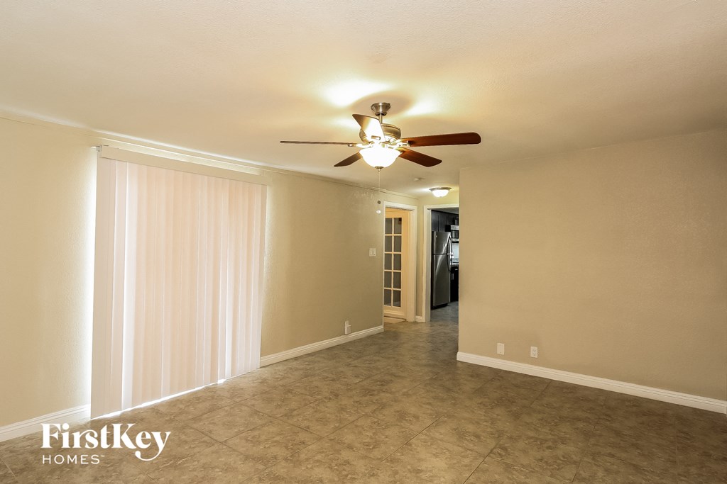 A spacious room with a ceiling fan and a doorway leading to another room.