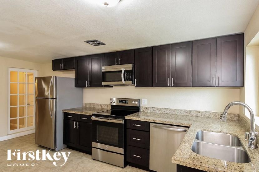 A kitchen with a refrigerator, oven, sink and microwave.