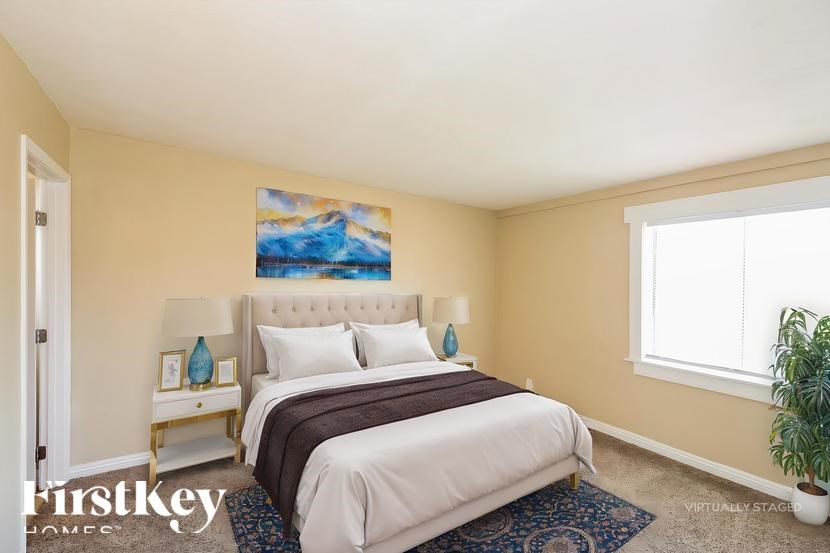 A bedroom with a large bed and a painting on the wall.