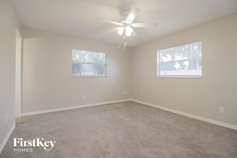a bedroom with carpet and a ceiling fan and two windows
