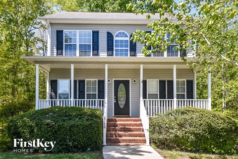 A white house with a porch and a brick staircase leading to the front door.