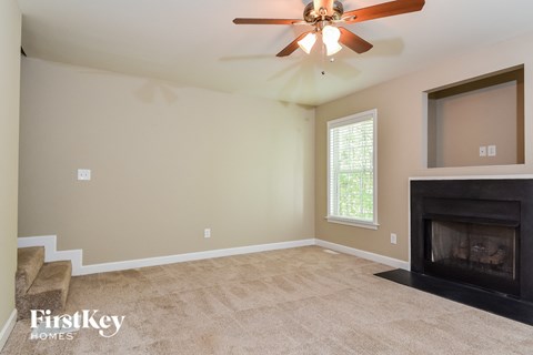 A living room with a fireplace and a ceiling fan.