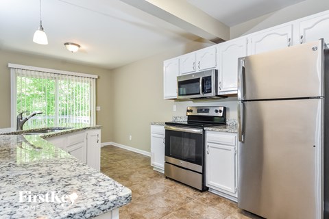 A kitchen with a granite counter top and stainless steel appliances.