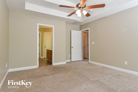 A spacious room with a ceiling fan and two doors.