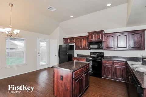 A kitchen with dark wood cabinets and a black refrigerator.