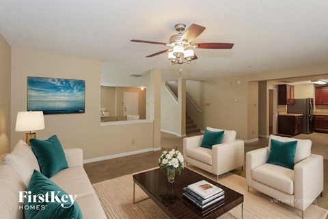 A living room with a white couch, a coffee table, and a painting on the wall.