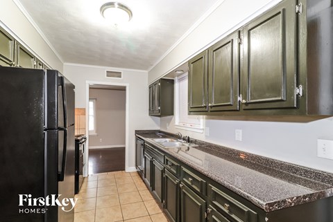 a kitchen with dark cabinets and granite counter tops and a black refrigerator