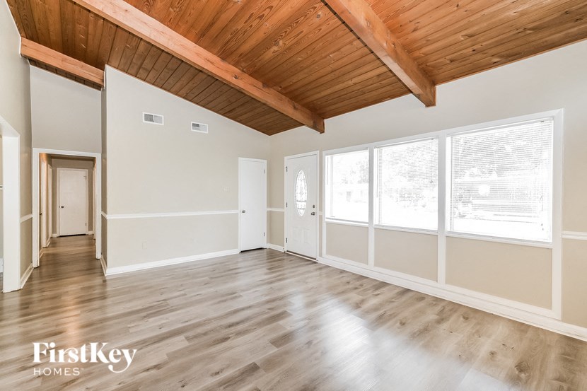 the living room of an empty home with wood floors and large windows