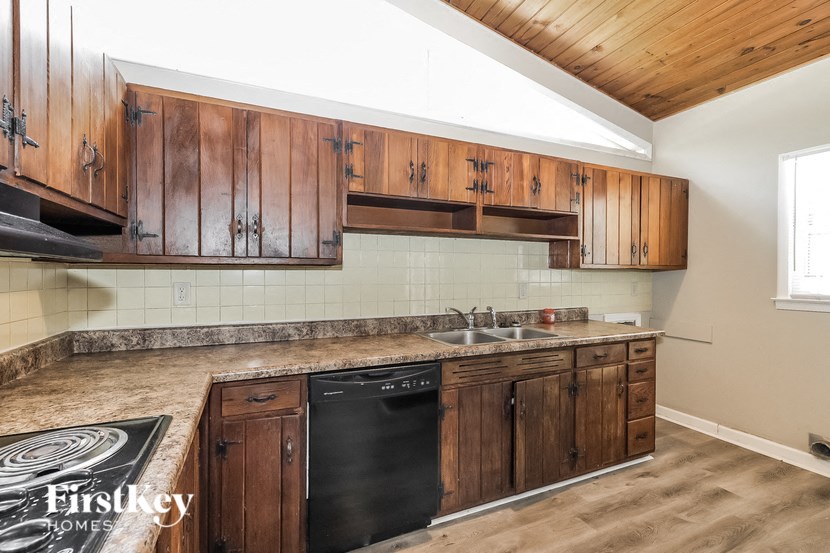 a kitchen with wooden cabinets and a black dishwasher and a sink