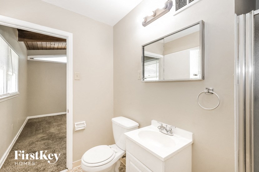 a bathroom with a toilet sink and mirror and a shower