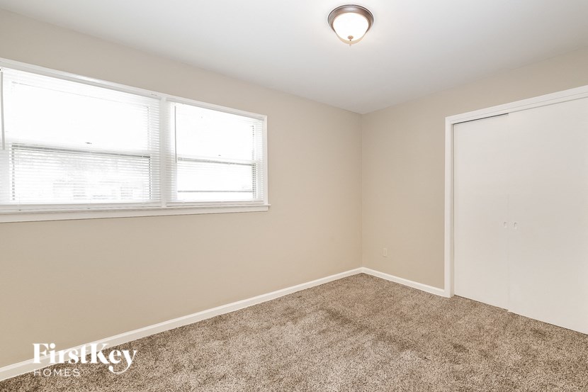 a bedroom with carpet and a window and a door