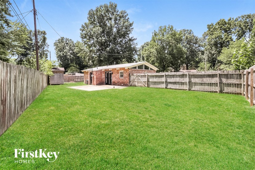 a backyard with a yard and a fence and a brick house