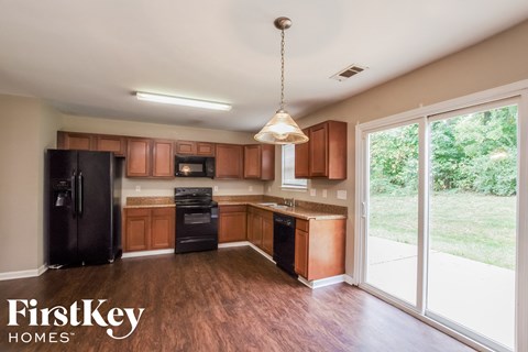A kitchen with wooden cabinets and black appliances is on the market with FirstKey Homes.