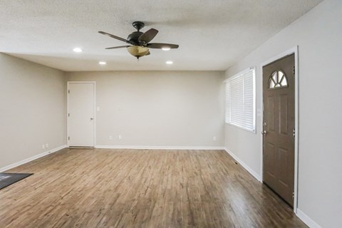 an empty living room with wooden floors and a ceiling fan