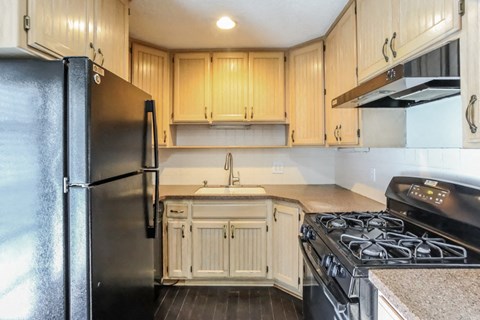 a kitchen with a stove and refrigerator and wooden cabinets