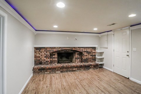 a living room with a brick fireplace and a wooden floor