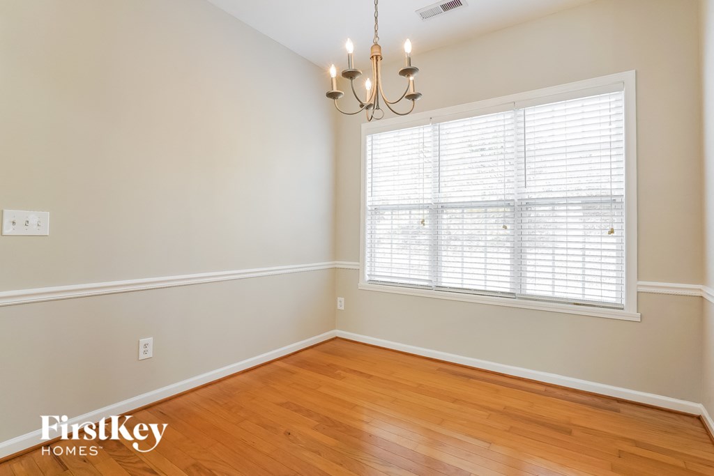 a bedroom with wood floors and a large window and a chandelier
