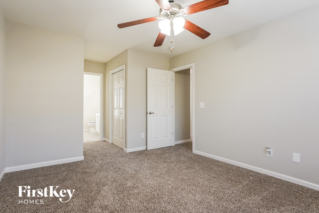 a master bedroom with carpet and a ceiling fan
