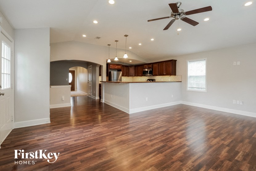 A spacious living room with a wood floor and a ceiling fan.