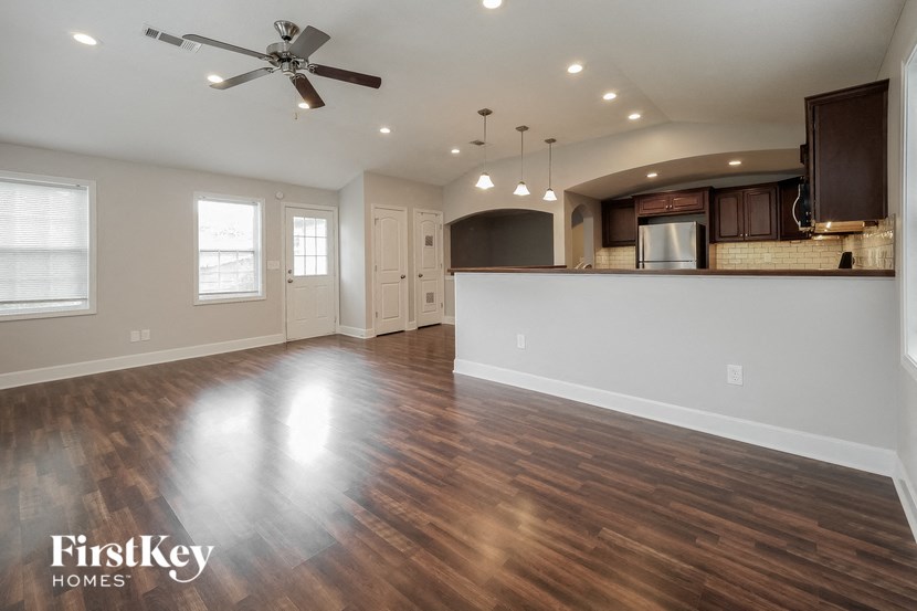 A spacious room with wooden floors and a ceiling fan.
