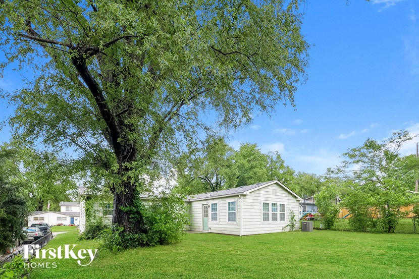 A small house is surrounded by trees and grass in a sunny day.
