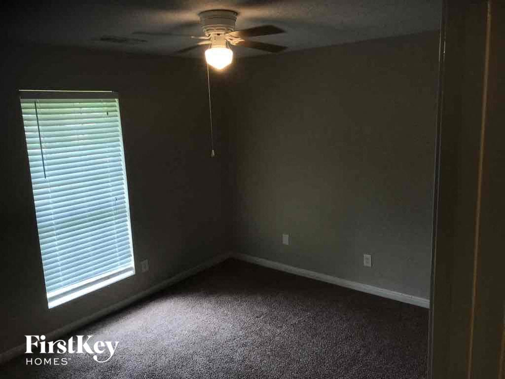 a dark room with a ceiling fan and a window