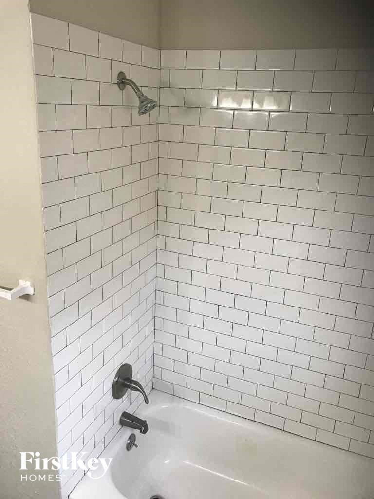 a white tiled bathroom with a tub and a shower