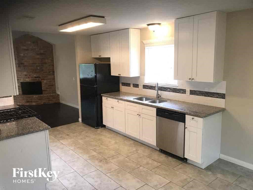 an empty kitchen with white cabinets and a black refrigerator